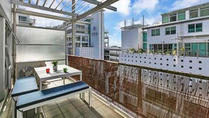 En balkon med et bord, stole og en potteplante.