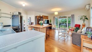 A modern kitchen with a central island, a dining area with a table and chairs, and a living room with a sofa and a TV.