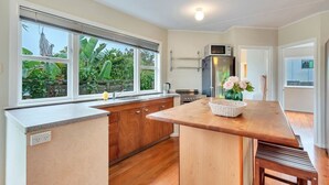 A kitchen with wooden cabinets, a countertop, a sink, a microwave, and a refrigerator. There is a window with a view of greenery outside.