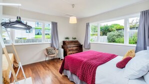A bedroom with a bed, a dresser, a chair, and a radiator.