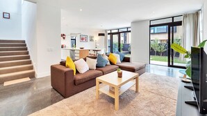 Uma sala de estar moderna com um sofá marrom, uma mesa de centro de madeira e uma TV em um móvel.