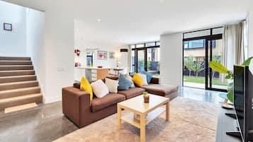 A modern living room with a brown sofa, a wooden coffee table, and a TV on a stand.