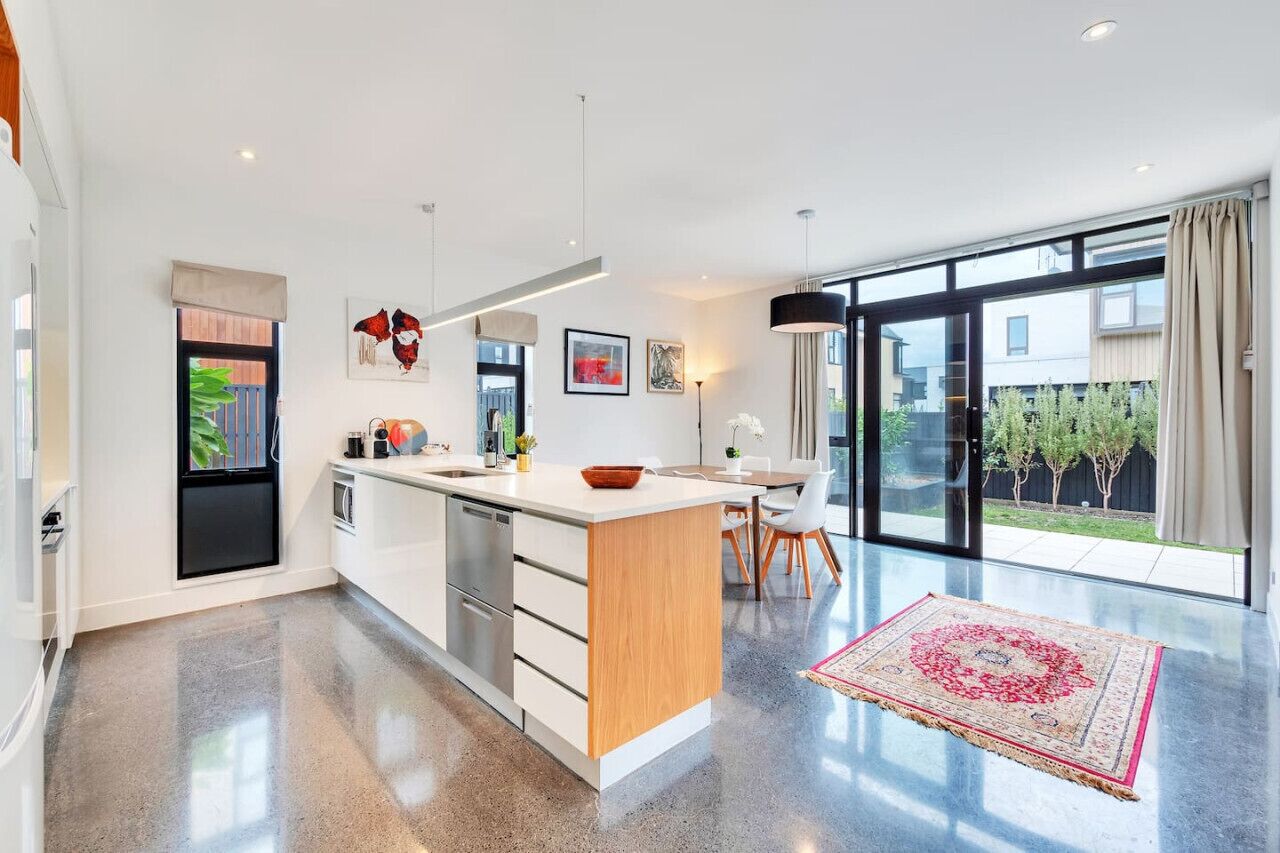 A modern kitchen with a large island, stainless steel appliances, and a dining area with a view to the outdoors.