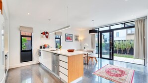Uma cozinha moderna com uma ilha grande, eletrodomésticos de aço inoxidável e uma área de refeições com vista para o exterior.