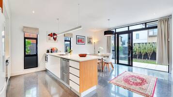 A modern kitchen with a large island, stainless steel appliances, and a dining area with a view to the outdoors.