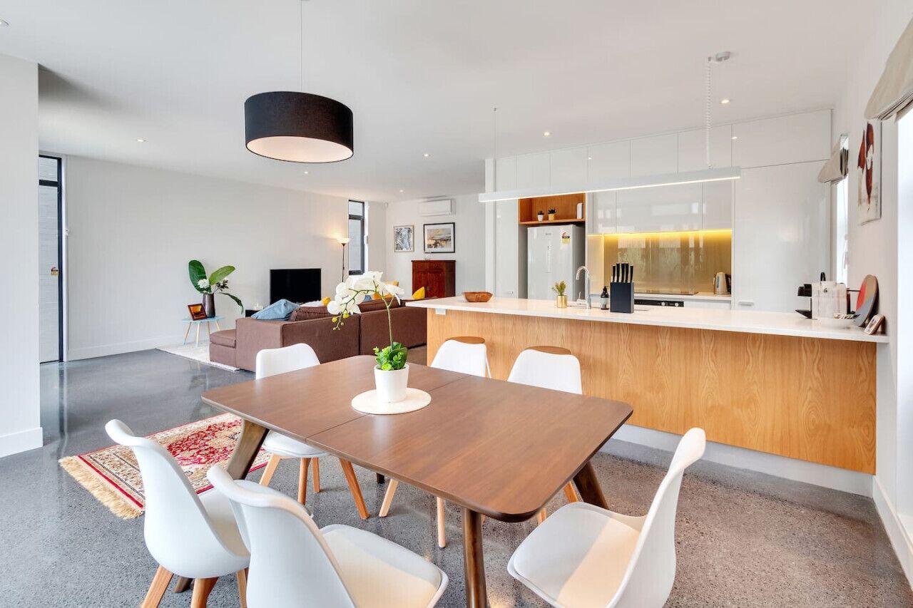 A modern kitchen with a central island, white cabinetry, and a pendant light.