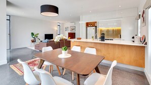 Cozinha moderna com ilha central, armários brancos e luminária pendente.