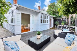 Une maison avec un garage ouvert, une terrasse avec des meubles d’extérieur et un jardin.
