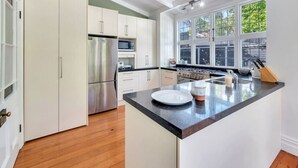 A modern kitchen with white cabinets, stainless steel appliances, a black countertop, and a large window providing natural light. - Classic Villa Retreat - Steps To Ponsonby Rd (Auckland Central Suburbs)