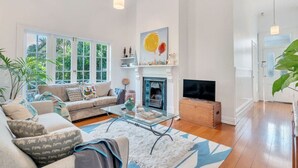 A spacious living room with a sofa, coffee table, fireplace, and large windows. - Classic Villa Retreat - Steps To Ponsonby Rd (Auckland Central Suburbs)