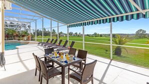 A covered outdoor seating area with wicker furniture and a view of a golf course. -  Fairway View Villa 5*  luxury – South-Facing Pool & Game Room, Nr Disney & Golf (Davenport)