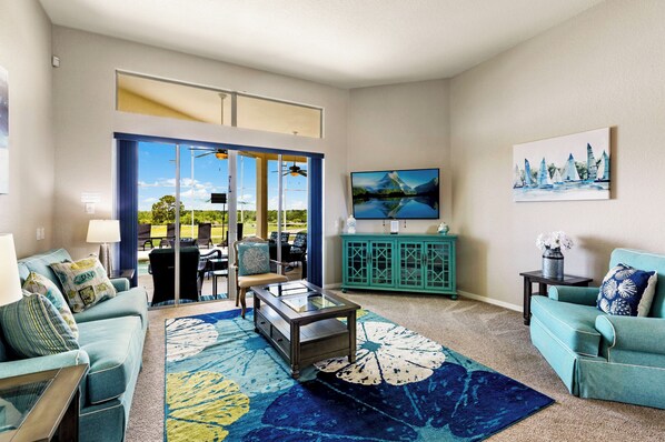 A living room with a large window, a TV, and a view of a lake.