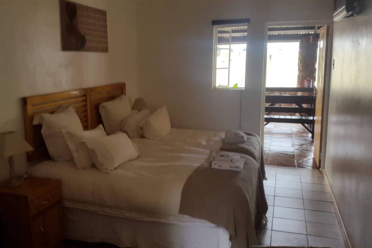 A bedroom with a wooden headboard, a bedside table, a lamp, and a bed with white bedding.