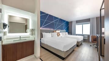 Een hotelkamer met een groot bed, een extra bed, een badkamer met spiegel en wastafel, en uitzicht op de omgeving.