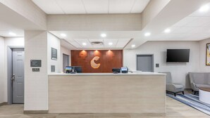 A reception area with a wooden reception desk, a mounted TV, and a seating area with two chairs. - Comfort Inn & Suites Belton Temple South I-35 (Belton)