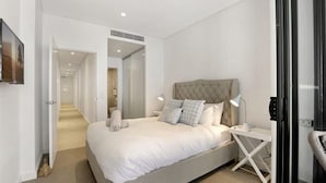 A modern bedroom with a large bed, bedside tables, and a walk-in closet. - 204 on the Beach by Experience Jervis Bay (Huskisson)