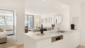 A modern kitchen with a large island, a built-in oven, and a coffee machine. - 204 on the Beach by Experience Jervis Bay (Huskisson)