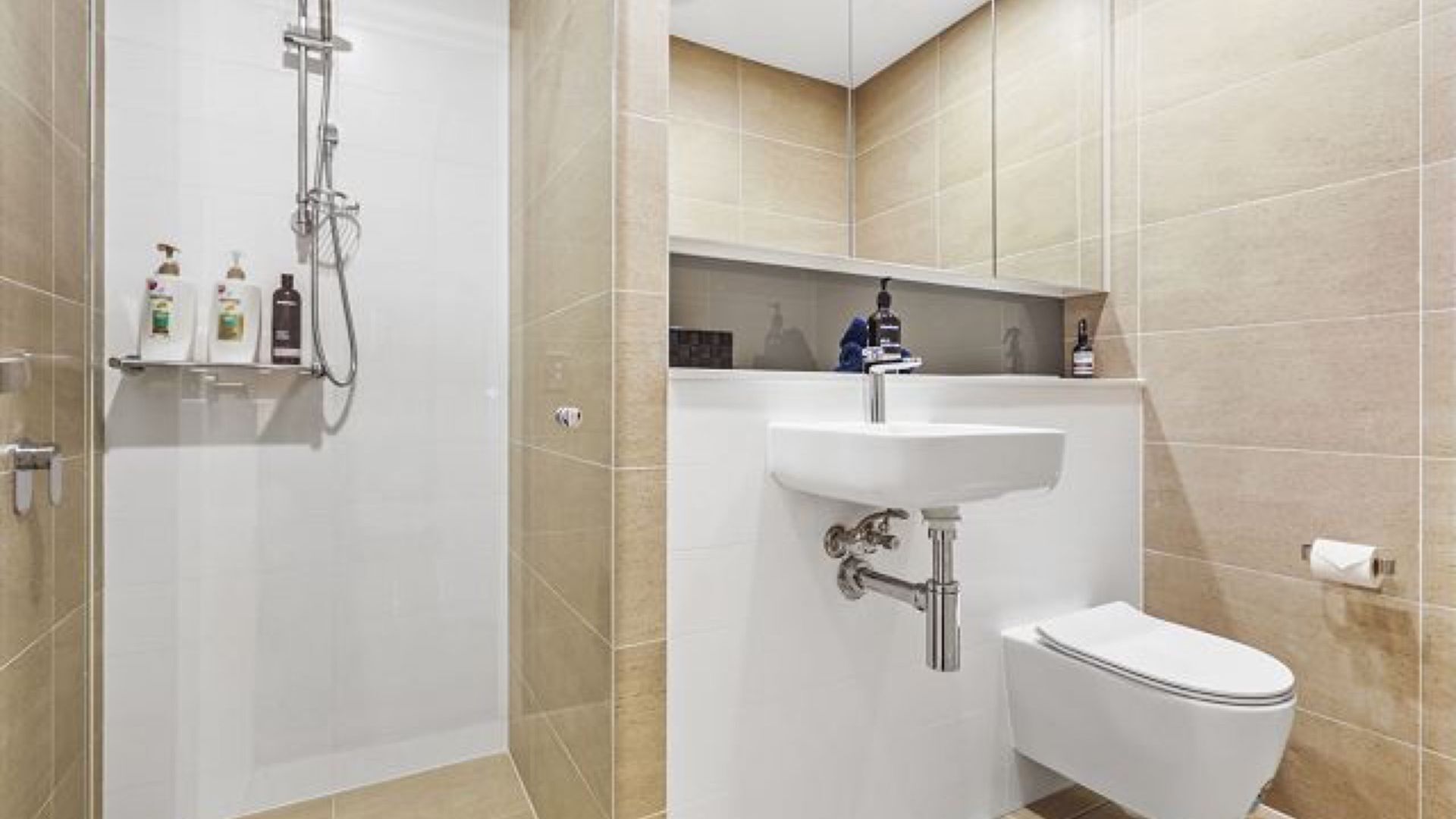 A modern bathroom with a shower, sink, and toilet.