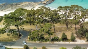 A coastal landscape with a road, trees, and a beach.