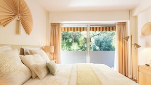 A bedroom with a large bed, a view of greenery through the window, and a balcony. - Côte d’Azur, Sea View, Tennis, Beach Access (Golfe Juan)
