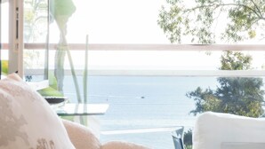 A room with a view of the sea, a table with a green vase, and a white sofa. - Côte d’Azur, Sea View, Tennis, Beach Access (Golfe Juan)