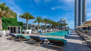 A rooftop pool area with lounge chairs, a pool, and palm trees. - Hollywood Beach HHouse Rentals (Hollywood)