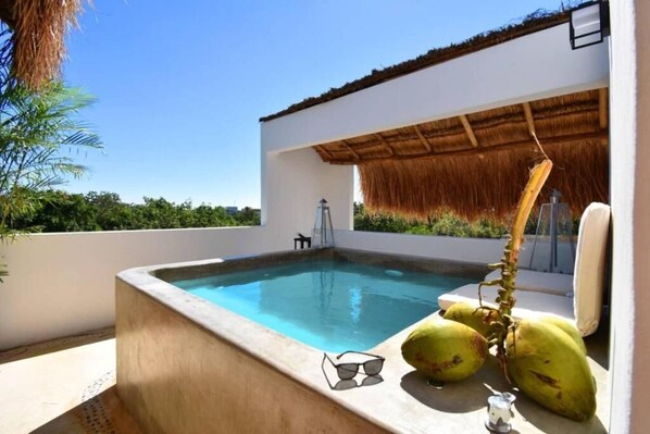 Relax by the serene pool surrounded by a thatched roof structure.