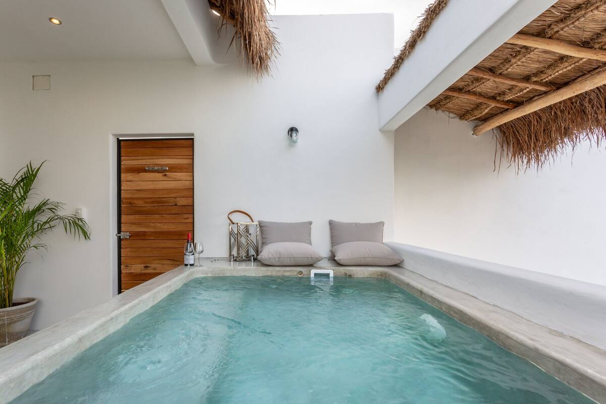 A spa area with a hot tub, a wooden door, and a ceiling with thatched elements.