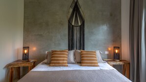 Een bed met twee kussens, een gebreide deken en een wanddecoratie. Er staan twee nachtkastjes met lampen bij.