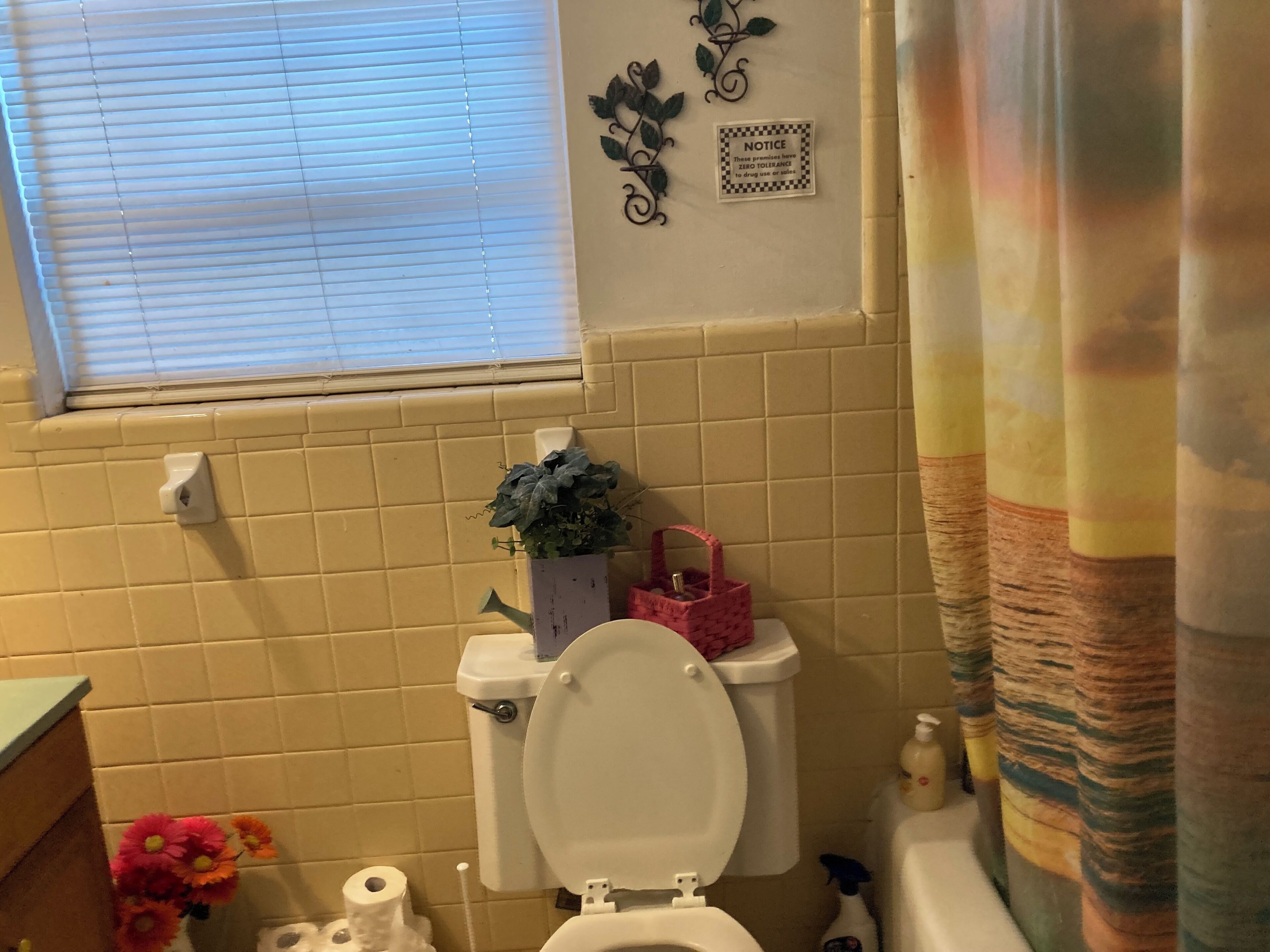 Ein Badezimmer mit Toilette, Waschbecken und einem Fenster mit Jalousien.