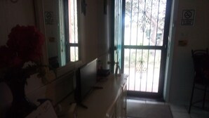 Una habitación con escritorio, una silla, ventana con vistas y una puerta.