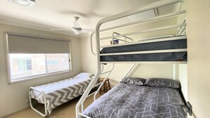 Ein Schlafzimmer mit Etagenbetten, einem Fenster und einem Deckenventilator.