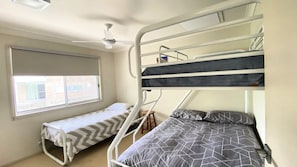 Dormitorio con literas, ventana y ventilador de techo.