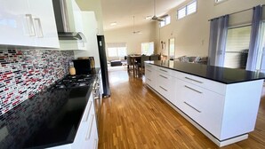 Une cuisine moderne avec un plan de travail noir, des armoires blanches et un pare-feu décoratif.