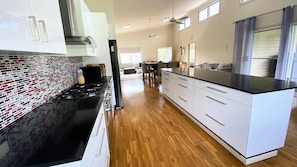 A modern kitchen with a black countertop, white cabinets, and a patterned backsplash. - 54 Kendall - Surrounded by Yuragrir National Park (WOOLI)