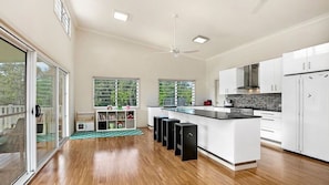 Una cocina moderna con una isla central, armarios blancos y un ventilador de techo.