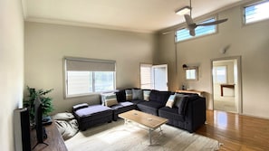Una sala de estar con un sofá modular, una mesa de centro y un ventilador de techo.