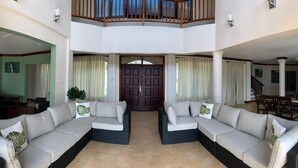 A spacious living area with a high ceiling, a central door, and a balcony overlooking the interior. - Villa Xona (Castries)