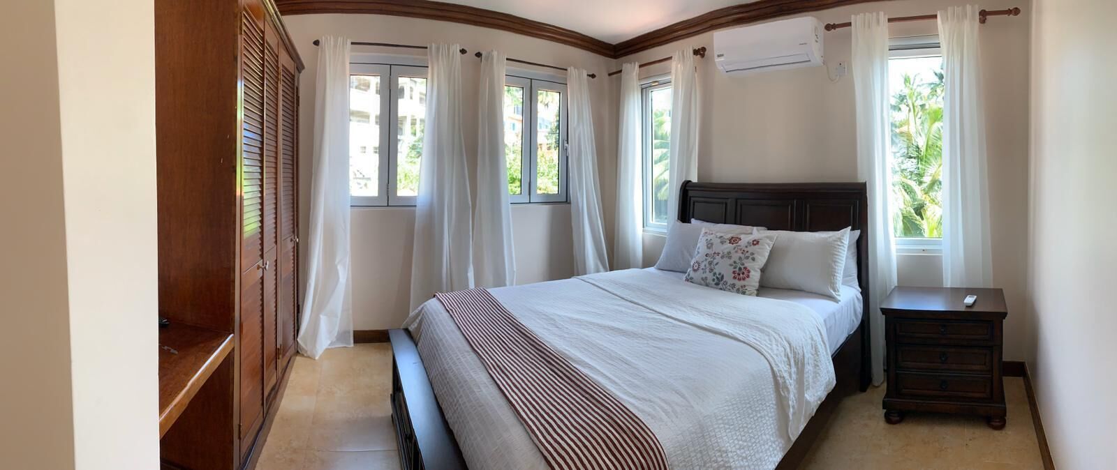 A bedroom with a large bed, a wooden nightstand, and a wardrobe.