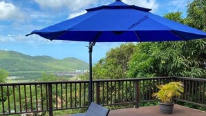 A deck with two reclining chairs and a blue umbrella, overlooking a lush landscape. - Villa Xona (Castries)