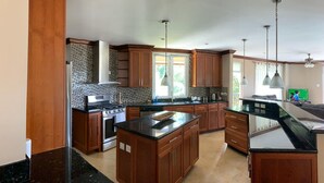 A spacious kitchen with wooden cabinets, granite countertops, and a large island. - Villa Xona (Castries)
