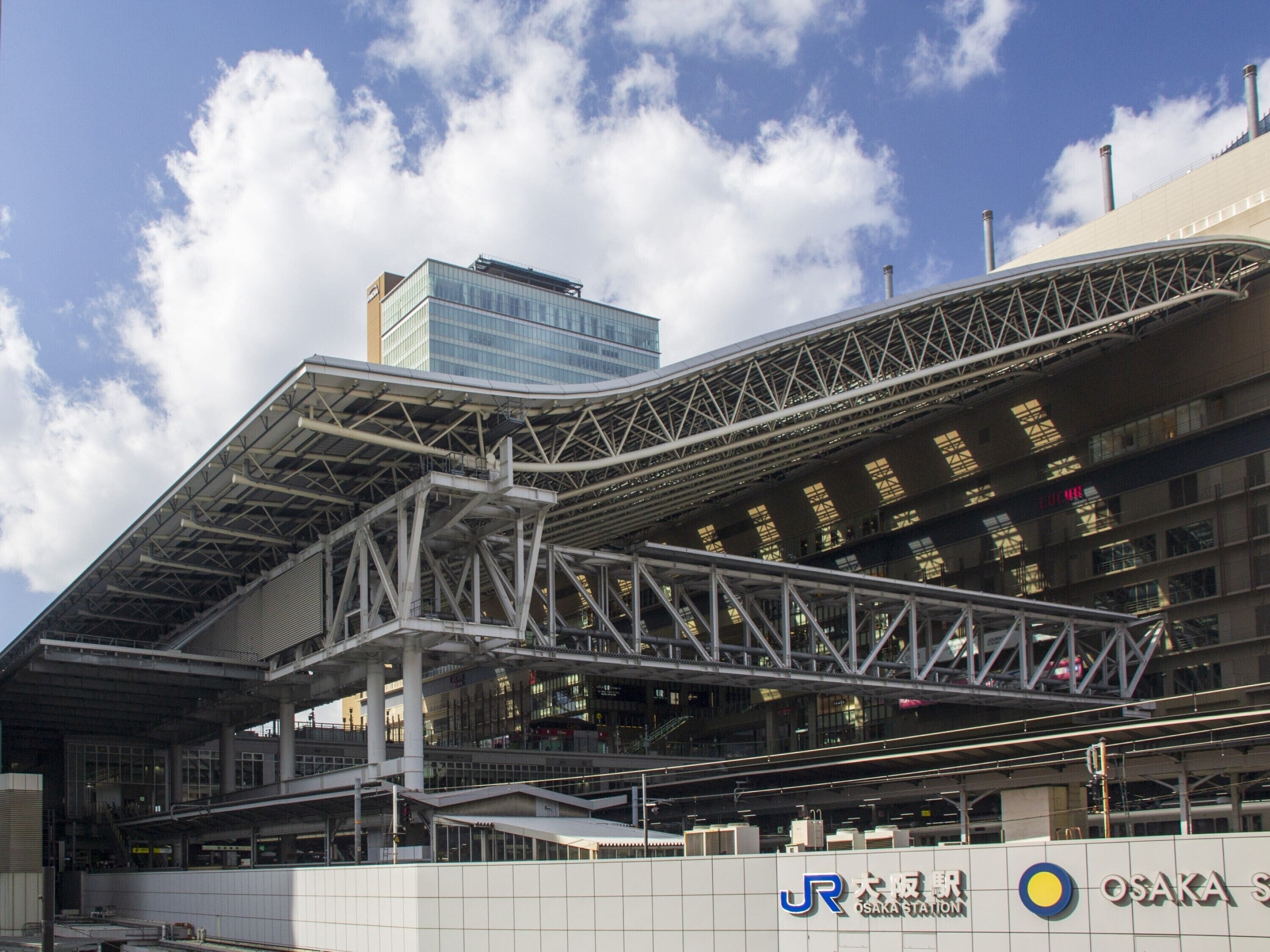 A modern train station with a large overhang and multiple levels.