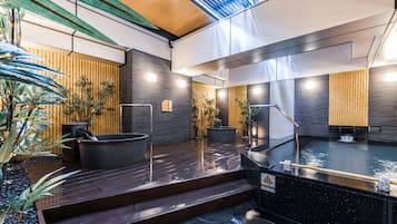A modern spa with a wooden deck, a hot tub, and a stone floor.
