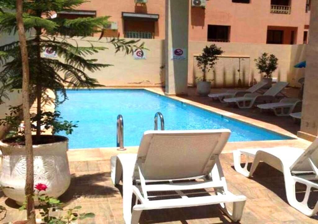 A swimming pool with lounge chairs and potted plants.