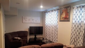 A living room with a sofa, a television, and patterned curtains.