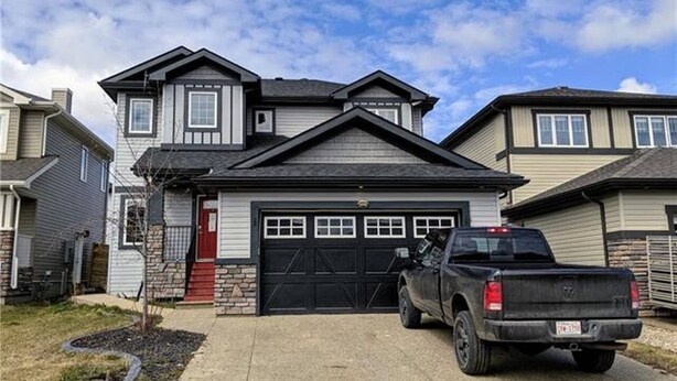 A two-story house with a garage, a driveway, and a parked truck.