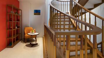A staircase with wooden railings and a chair with a table beside it.