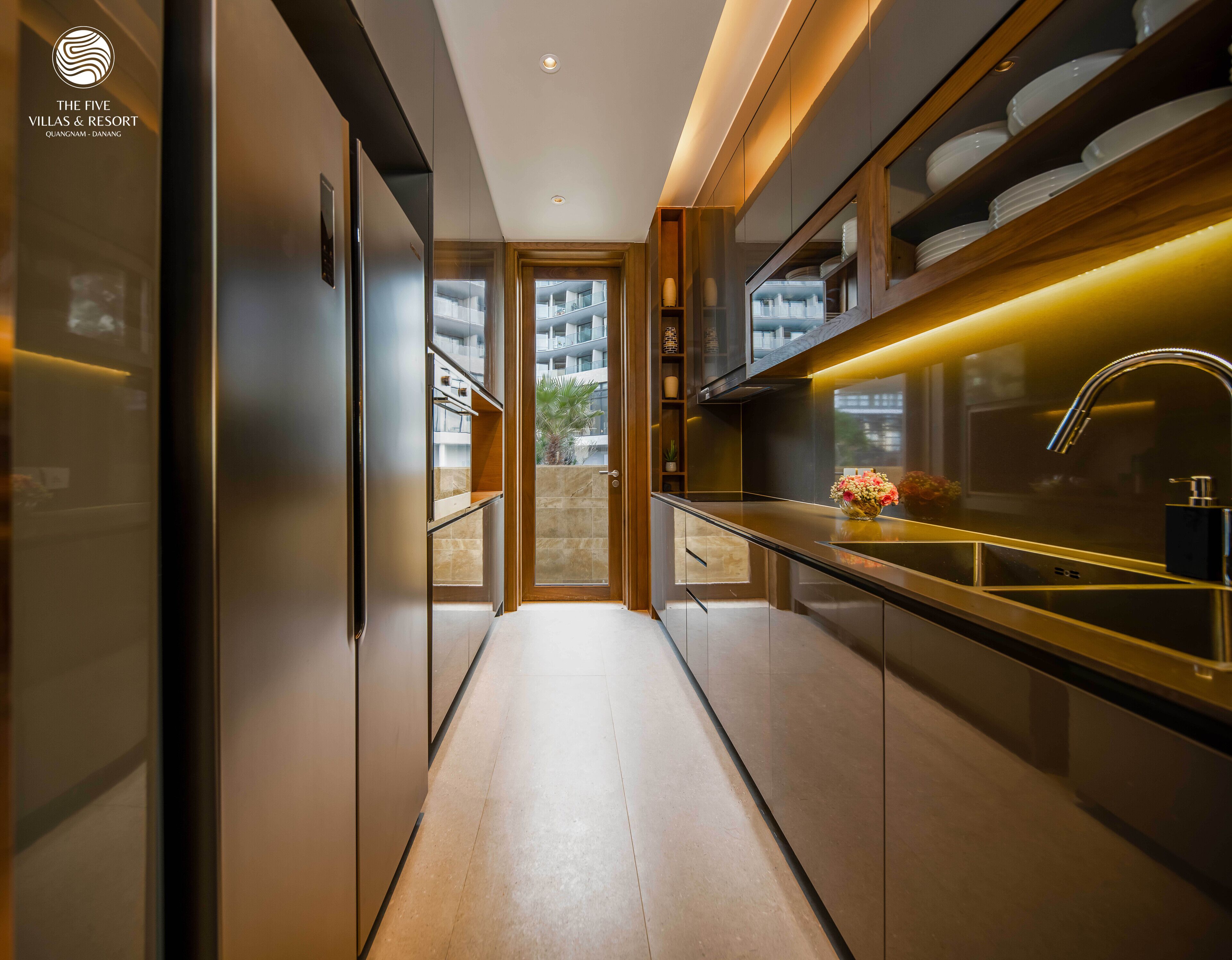 A modern kitchen with a central island, built-in appliances, and a view to the outside.
