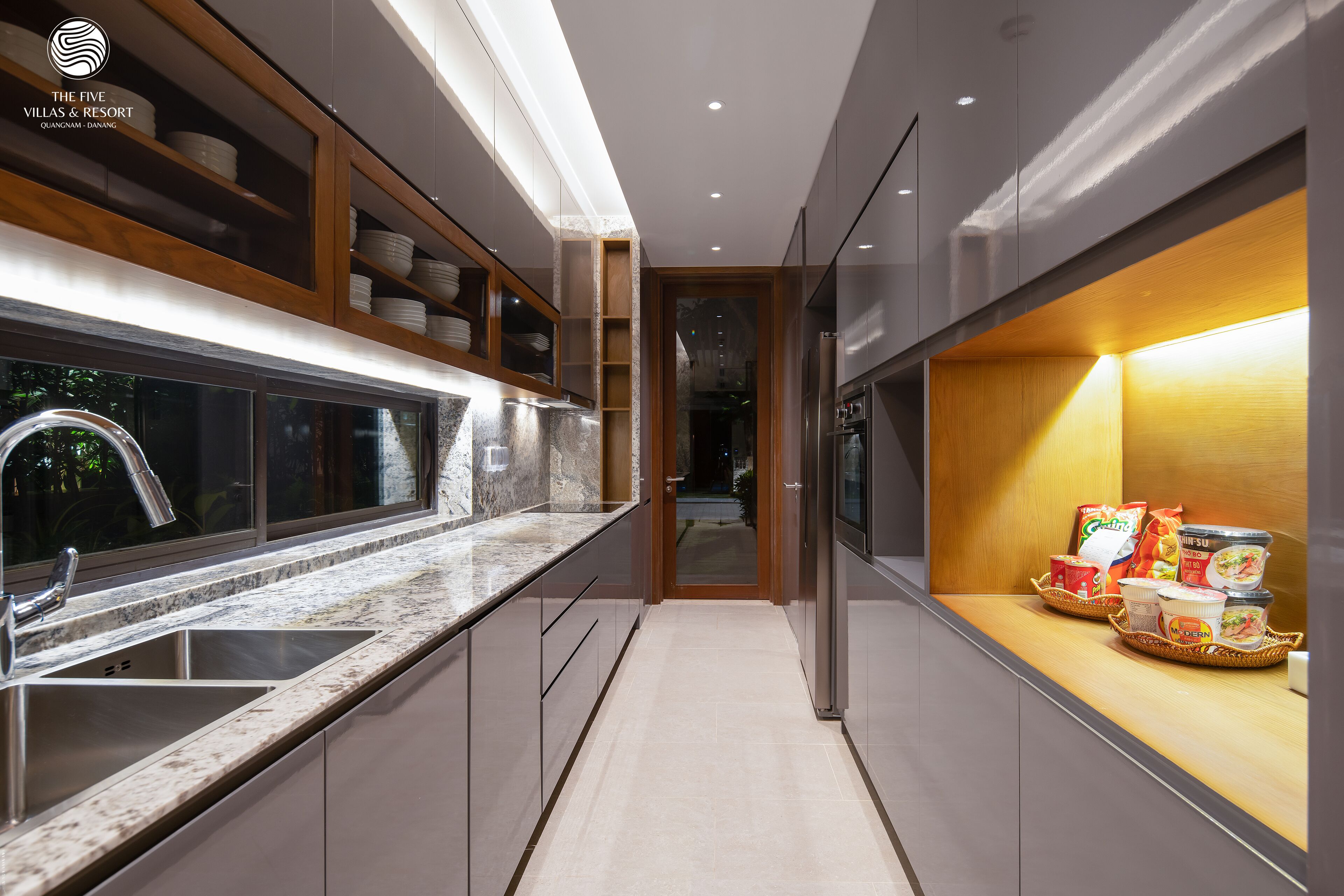 Eine moderne Küche mit Granit-Arbeitsplatte, Edelstahl-Spüle und Holzregalen.