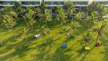 A lush, green lawn with palm trees and a modern building in the background.